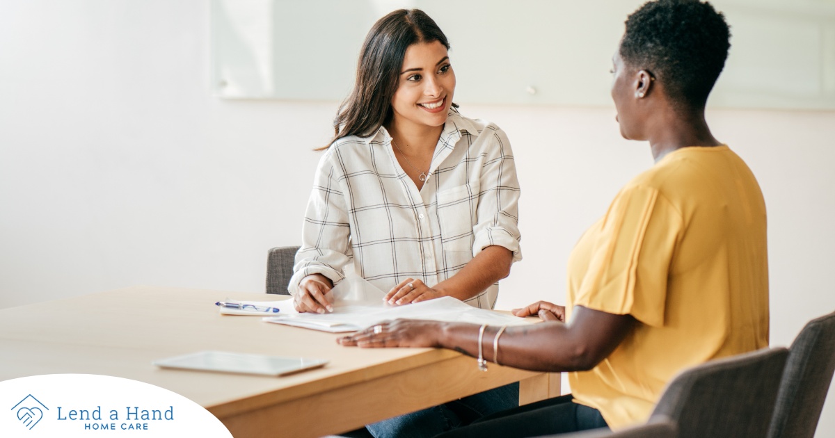 A woman happily interviews another woman, representing how well caregiver interviews can go when prepared.